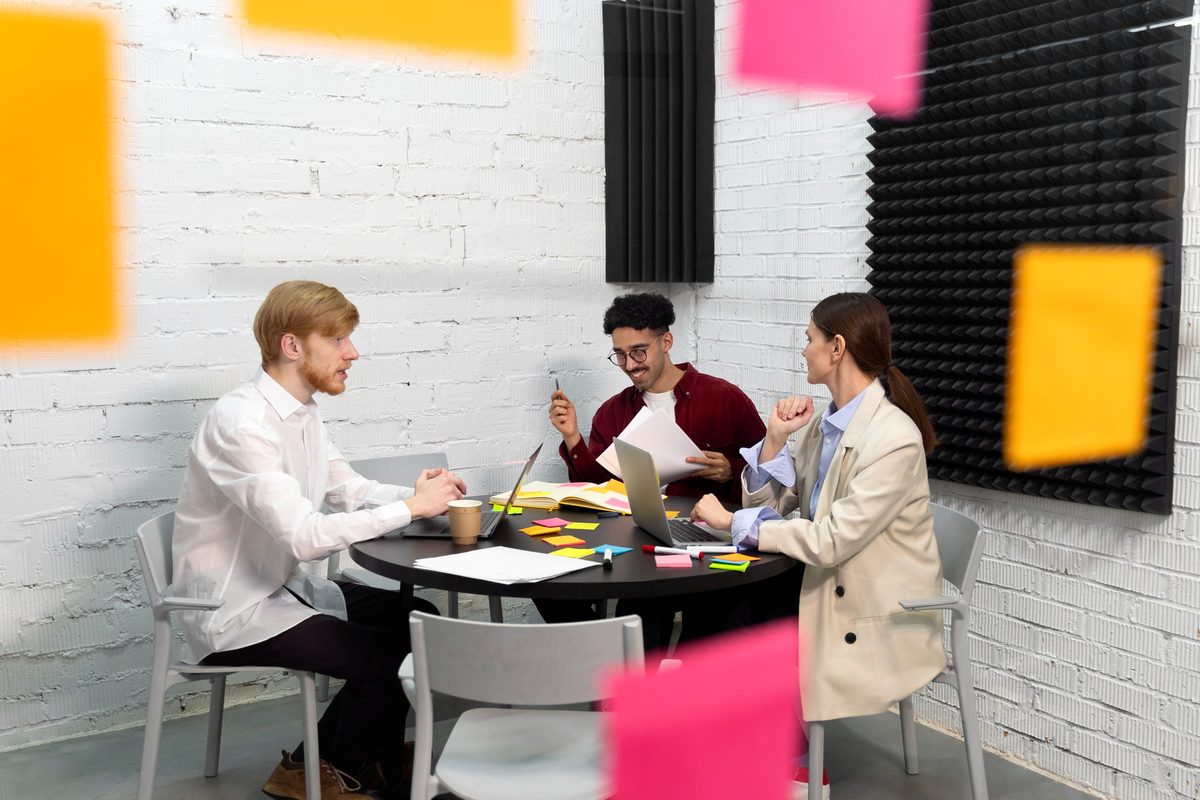 Three colleagues planning around a table covered in sticky notes